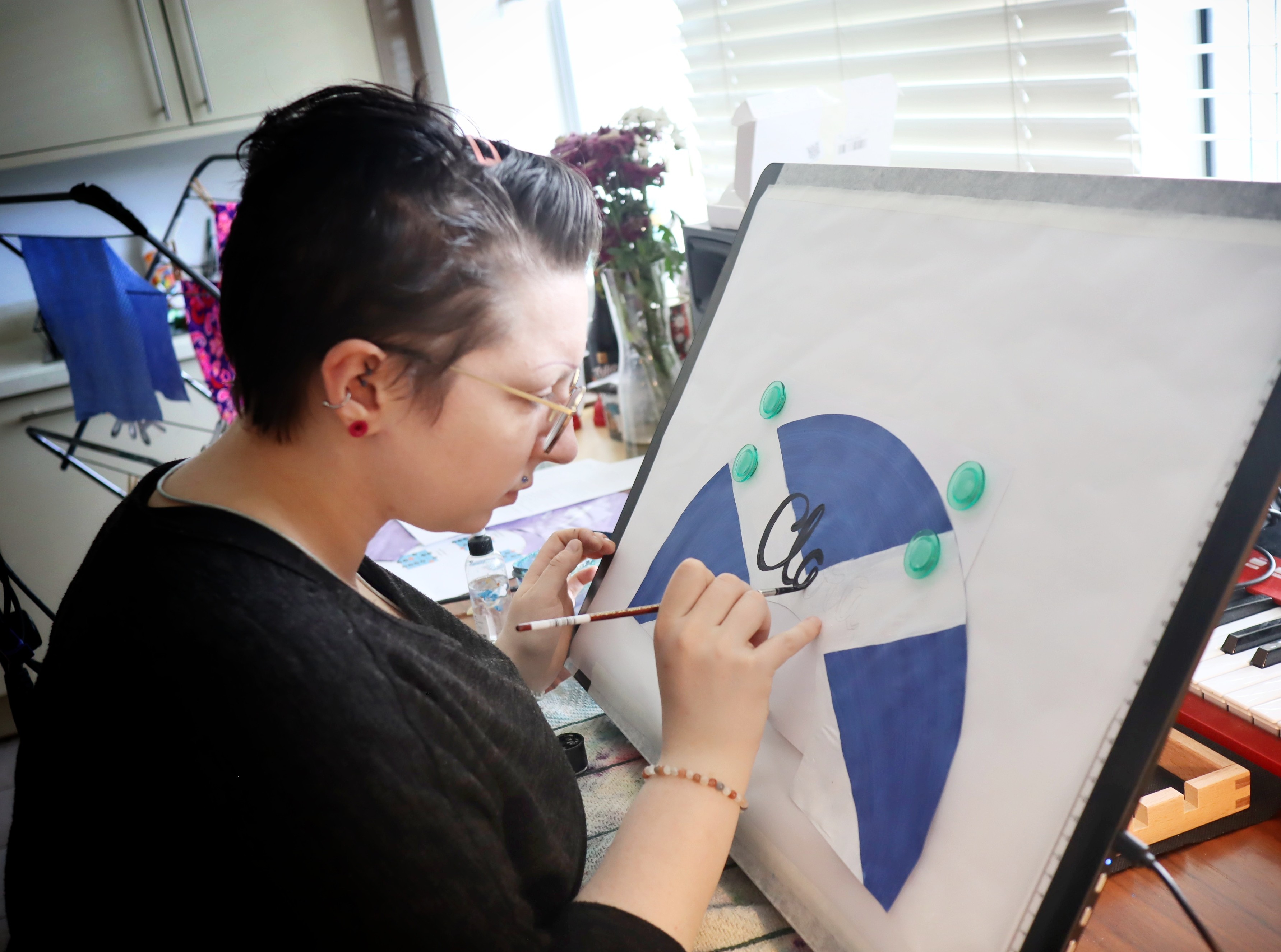 Person painting 'Clara' on a Scottish flag fan